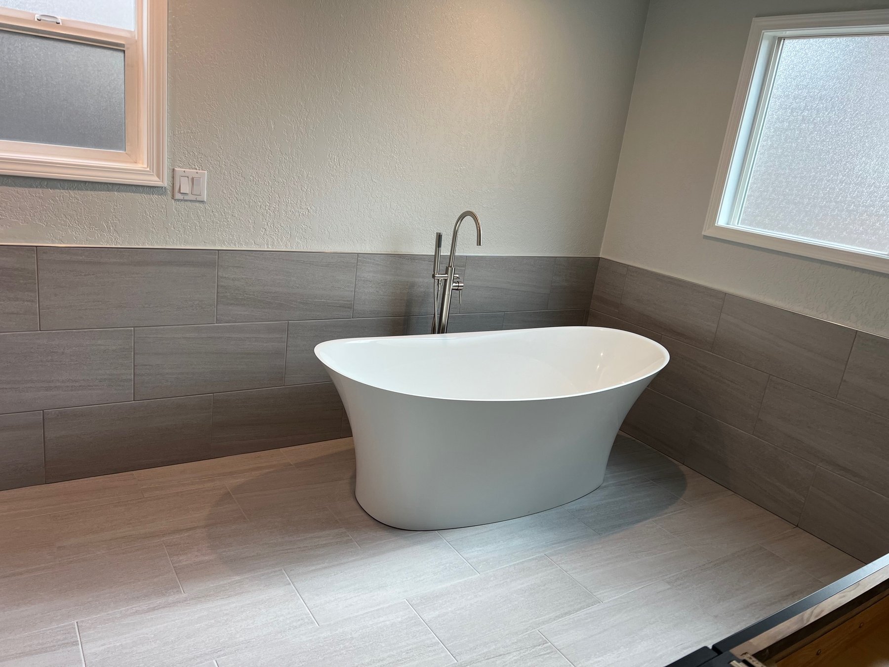 Freestanding soaking tub beneath a bathroom window