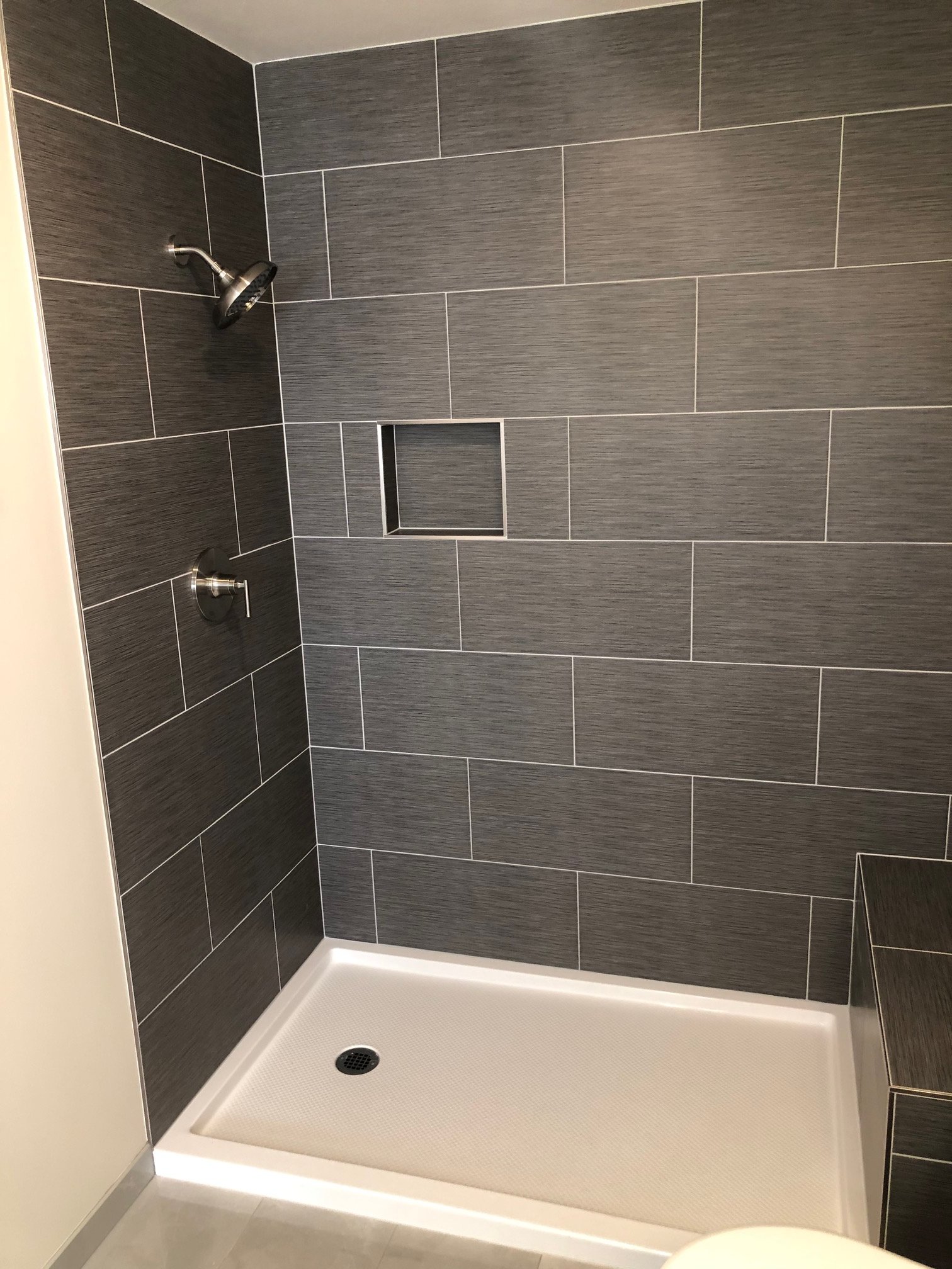 Gray tiled walk-in shower with glass enclosure