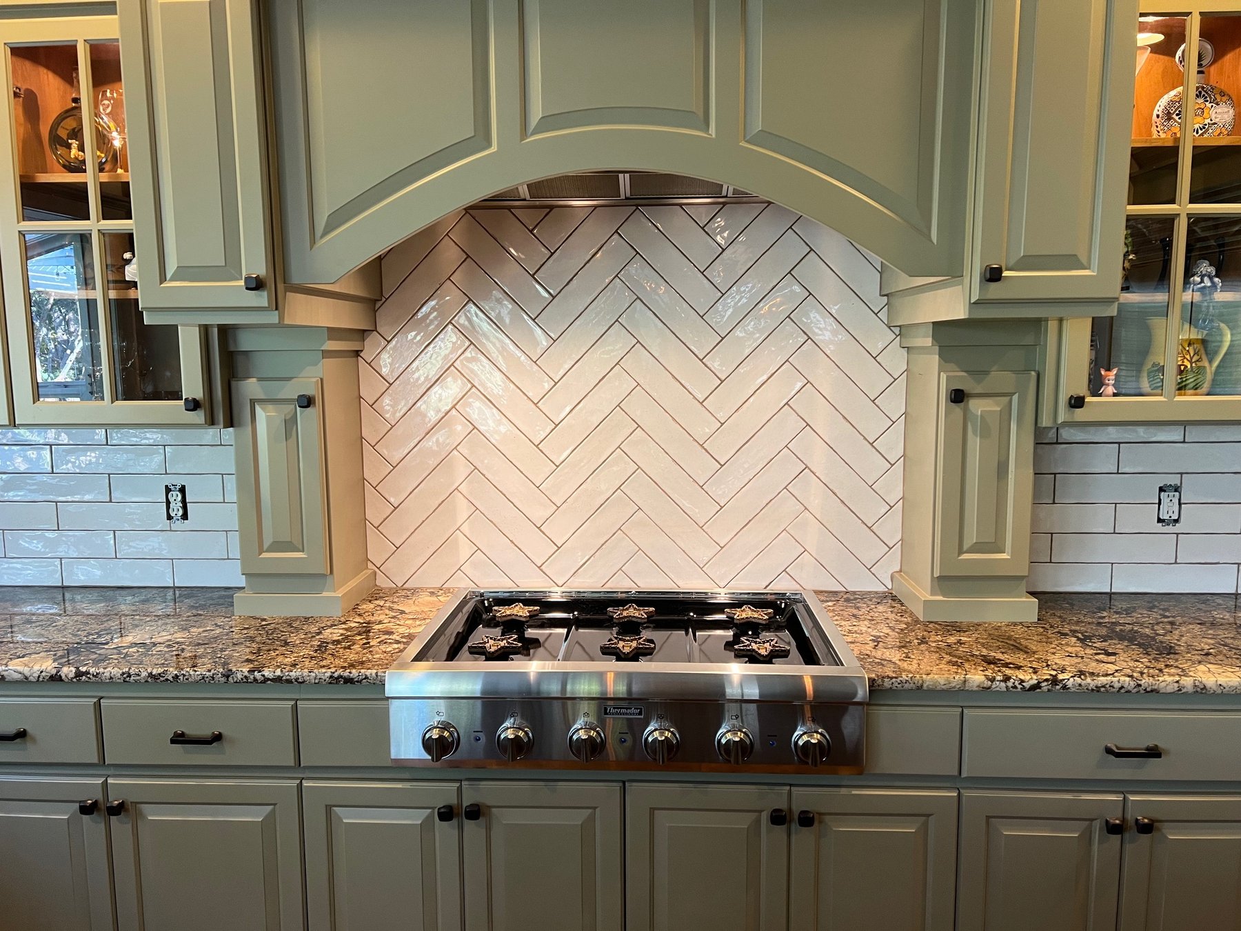 Sage green kitchen with herringbone tile backsplash